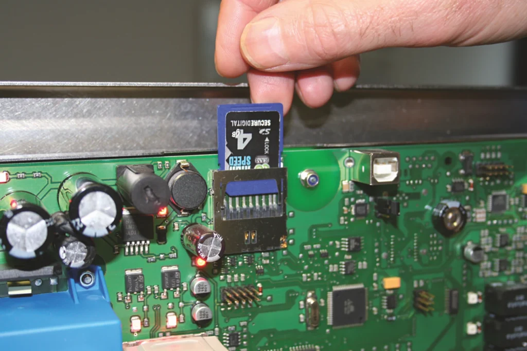 Hand inserts SD card into the DISCHER data logger's circuit board